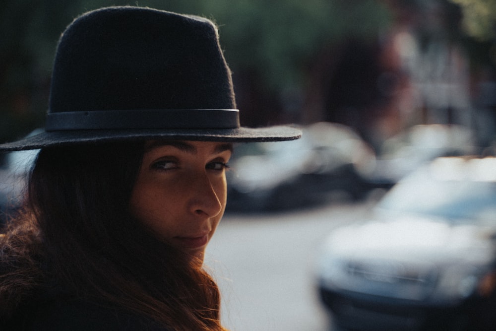 woman in black hat standing near white car during daytime