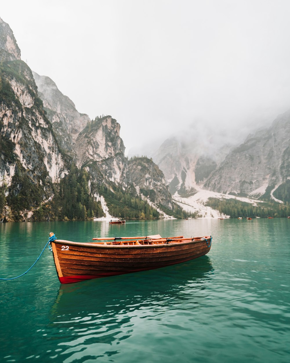 braunes Holzboot tagsüber auf einem Gewässer in der Nähe des Berges
