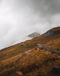 A moody monochrome landscape of winding mountain roads disappearing into fog.