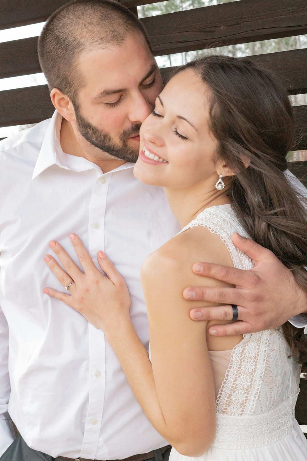 homem na camisa social branca beijando a mulher no vestido branco sem mangas