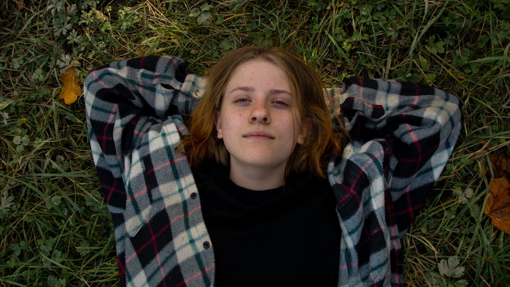 girl in black crew neck shirt lying on green grass