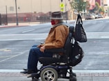 man in brown jacket and blue denim jeans sitting on black wheel chair