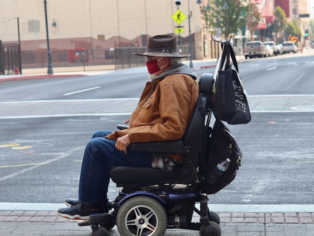 man in brown jacket and blue denim jeans sitting on black wheel chair