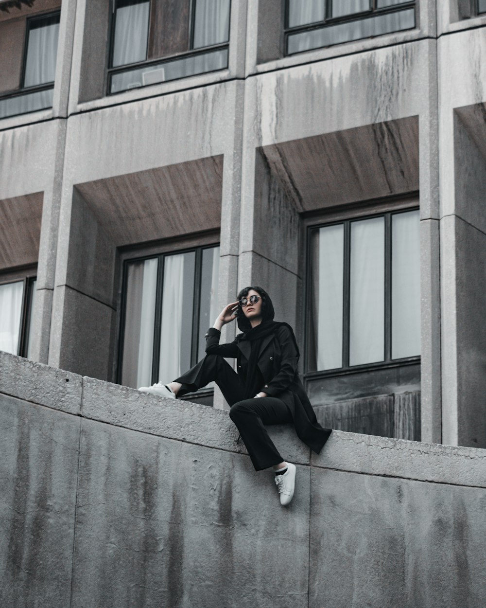 man in black jacket and black pants sitting on gray concrete stairs