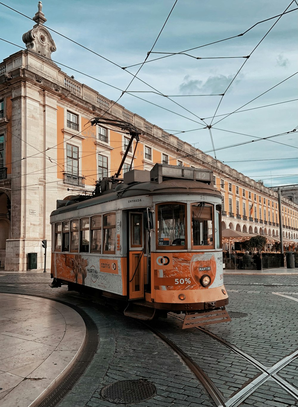 orange and white tram on road near brown concrete building during daytime