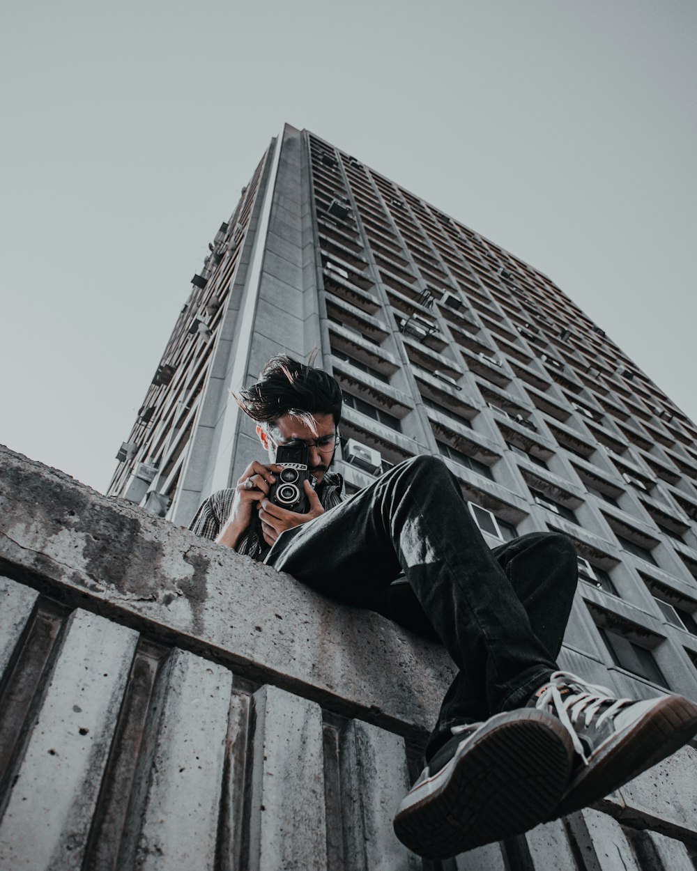 man in black jacket and black pants sitting on the roof of a building