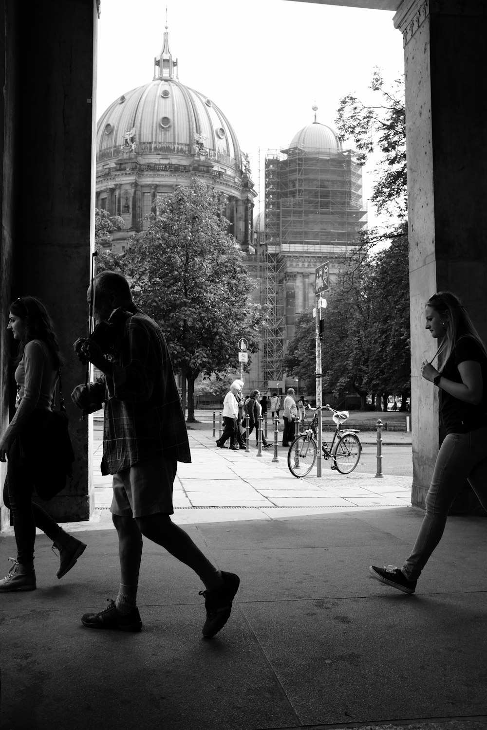 grayscale photo of man and woman walking on sidewalk