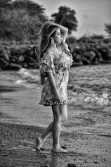 grayscale photo of girl in dress standing on road