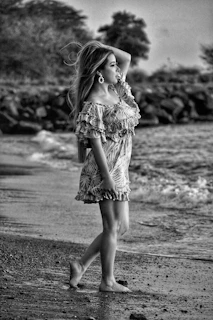 Giovana walking along a palm-lined beach in a flowing dress