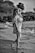 grayscale photo of girl in dress standing on road