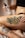 A person is holding a bottle of tattoo care product labeled 'Stories & Ink' above a tattoo on their leg. The tattoo features vibrant images with text that appears to say 'WORKERS UNITE' surrounded by colorful designs and characters.