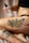 A person is holding a bottle of tattoo care product labeled 'Stories & Ink' above a tattoo on their leg. The tattoo features vibrant images with text that appears to say 'WORKERS UNITE' surrounded by colorful designs and characters.
