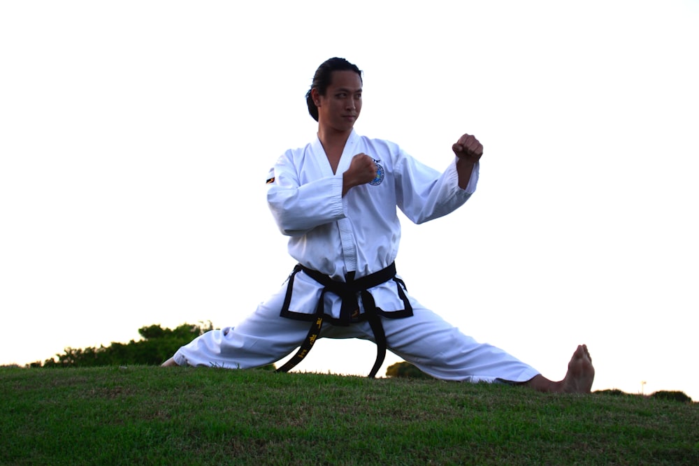 man in white dress shirt and black pants sitting on black chair on green grass field