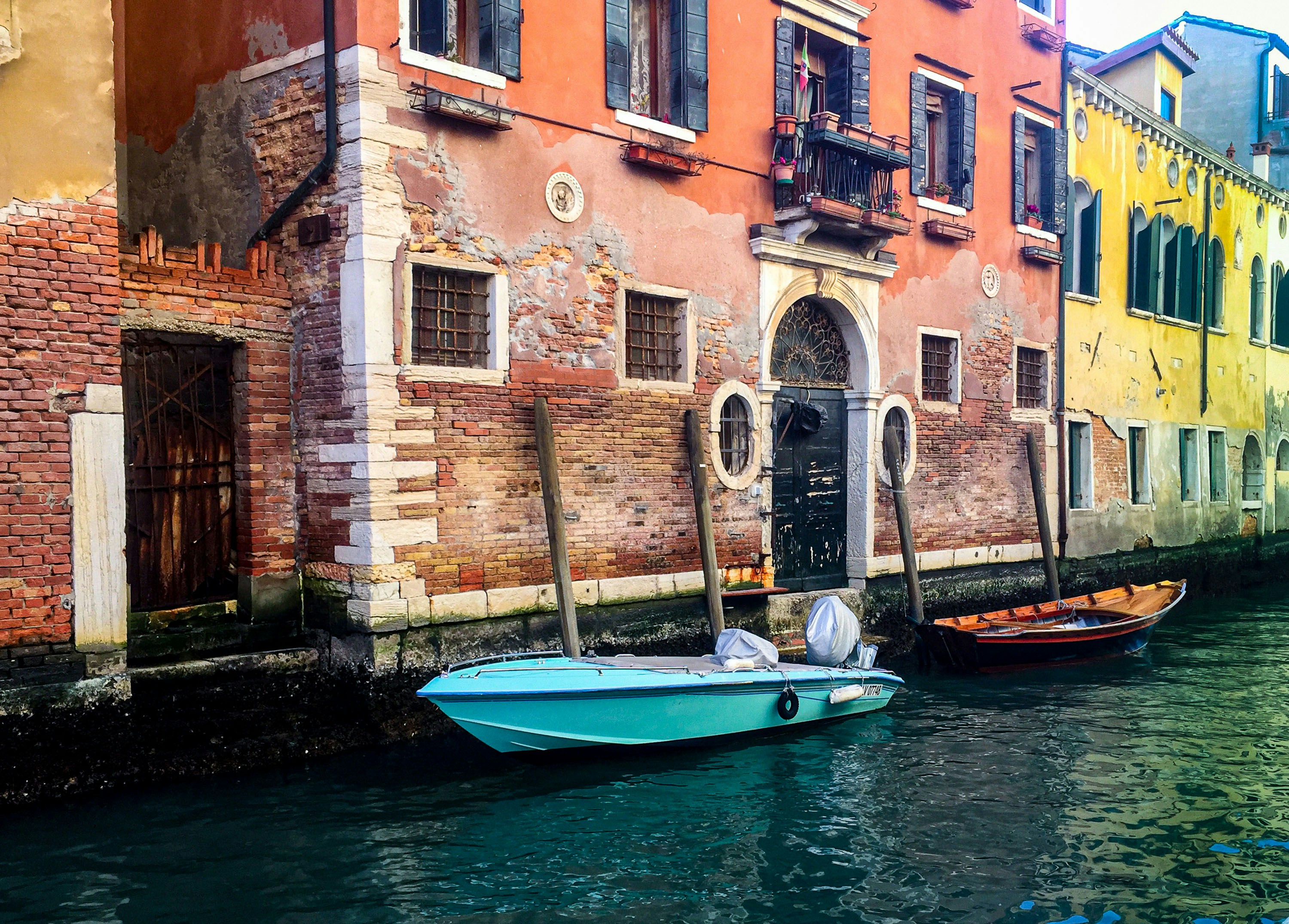 blue and white boat on river between brown concrete buildings during daytime, 