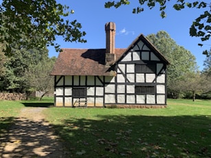 white and brown wooden house near green trees under blue sky during daytime