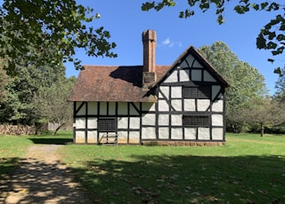 white and brown wooden house near green trees under blue sky during daytime