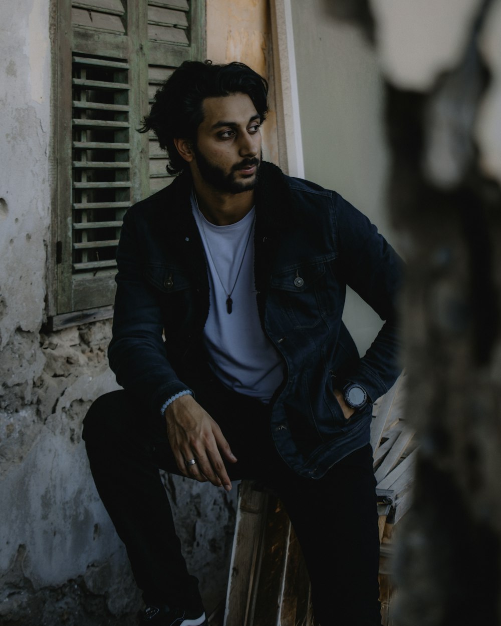 man in black leather jacket sitting on brown wooden seat