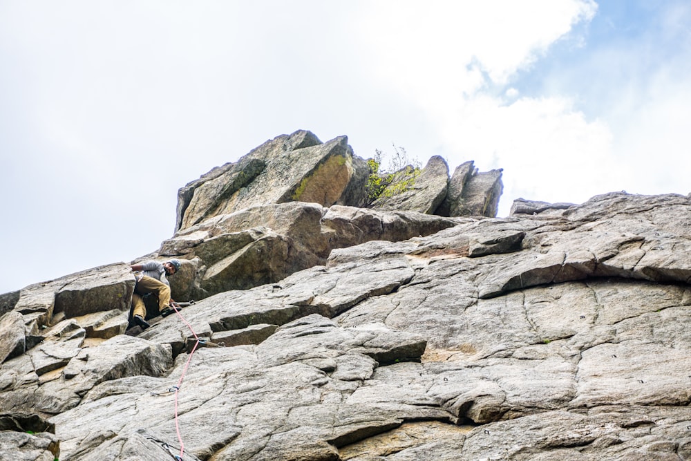 person climbing rocky mountain during daytime