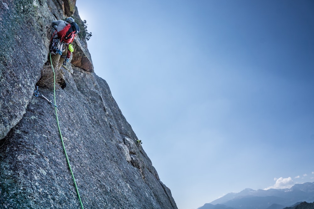 man climbing on rocky mountain during daytime