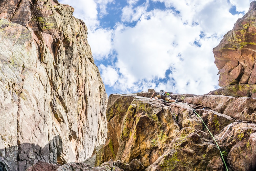 person standing on rock formation under blue sky and white clouds during daytime