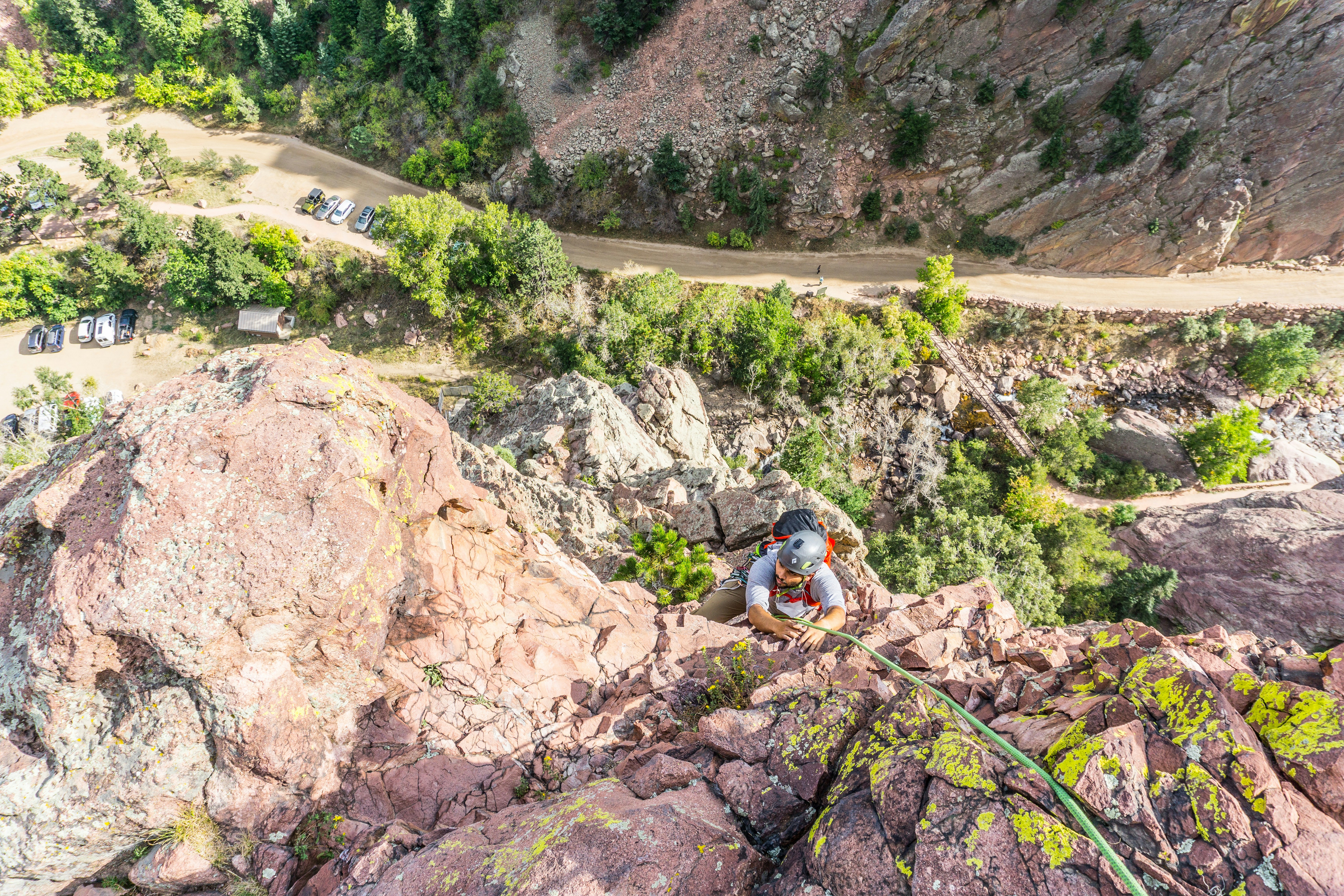 man in blue shirt sitting on rock mountain during daytime