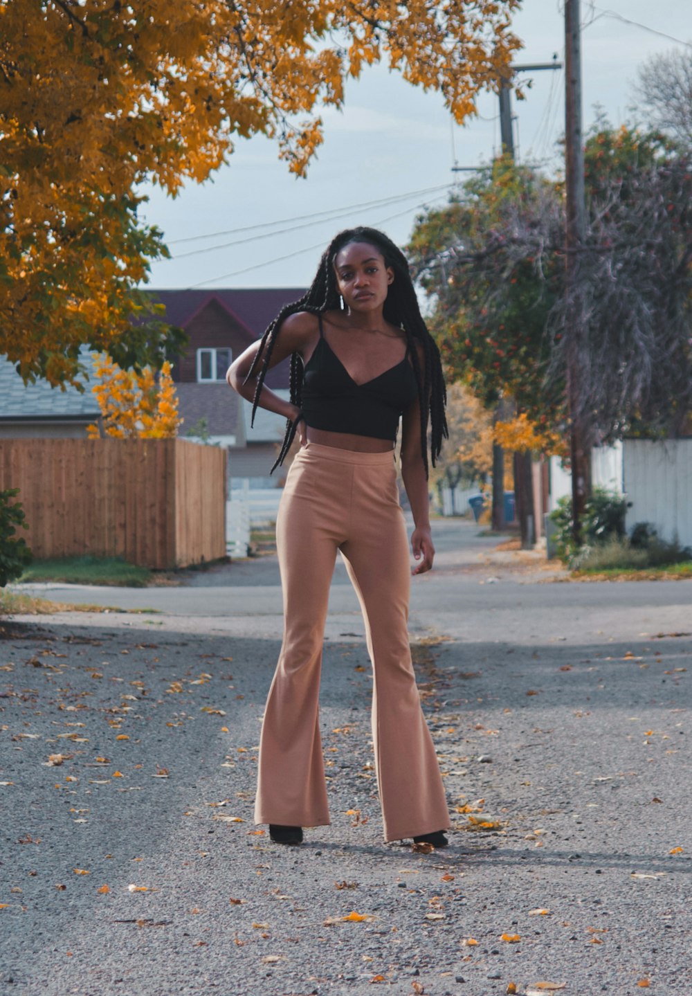 woman in black tank top and beige pants standing on gray concrete road during daytime