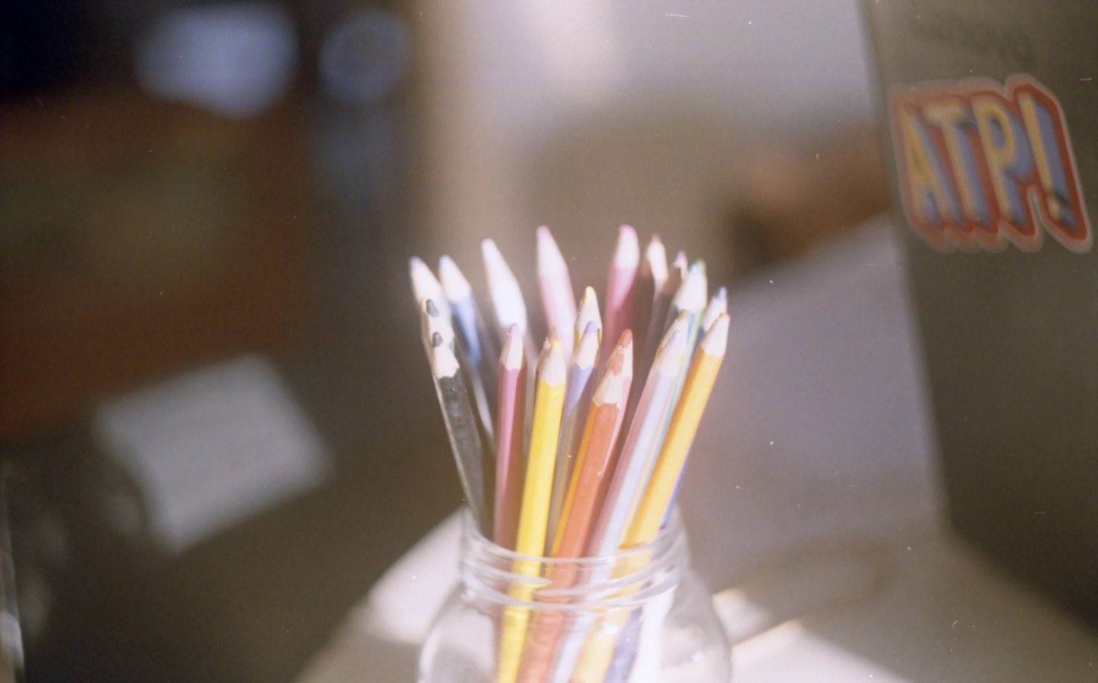 Colored pencils in a glass jar on a desk