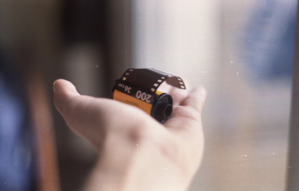 person holding black and orange plastic container