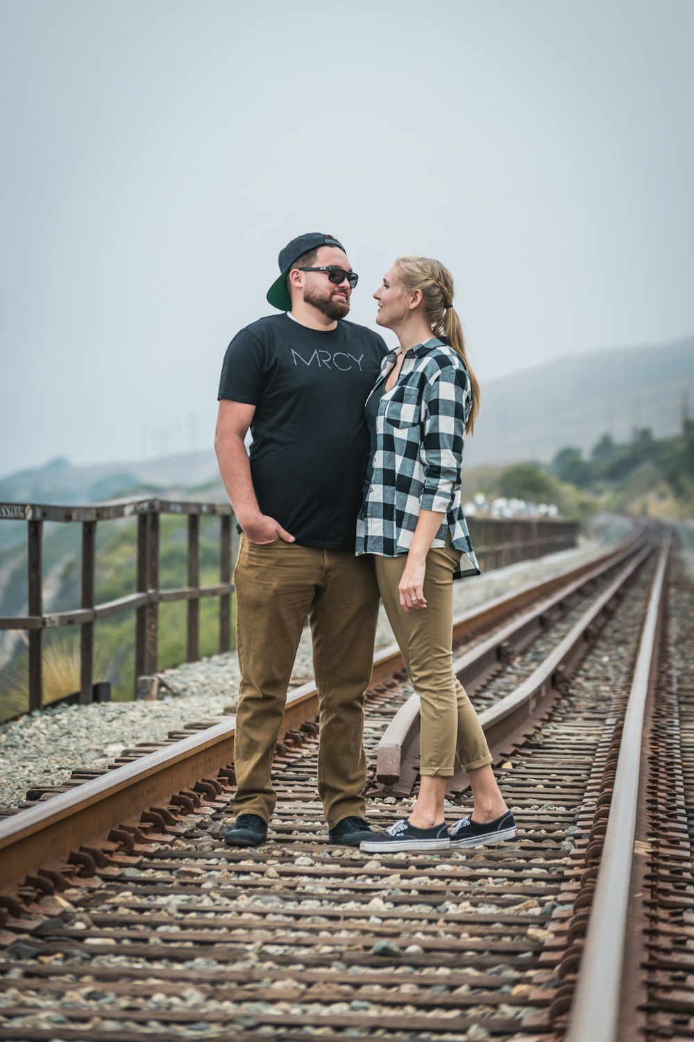 man and woman standing on train rail during daytime