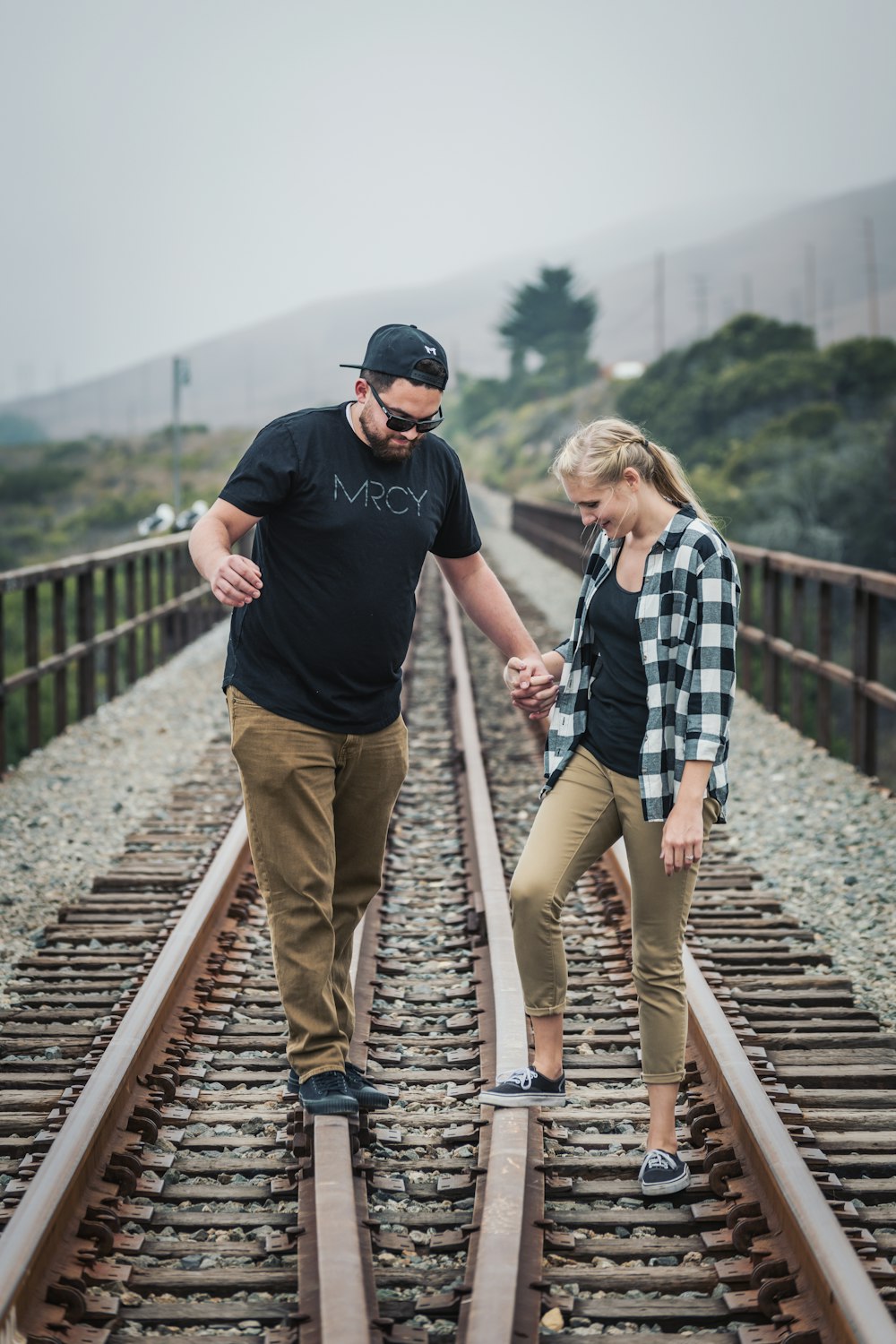 man and woman walking on train rail during daytime