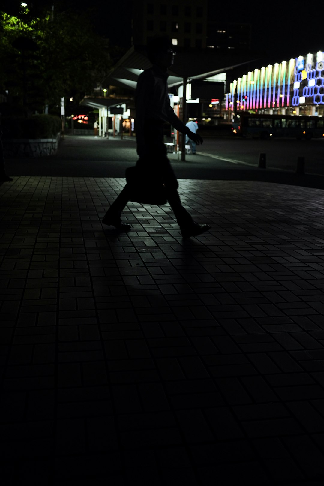 man walking on sidewalk during night time