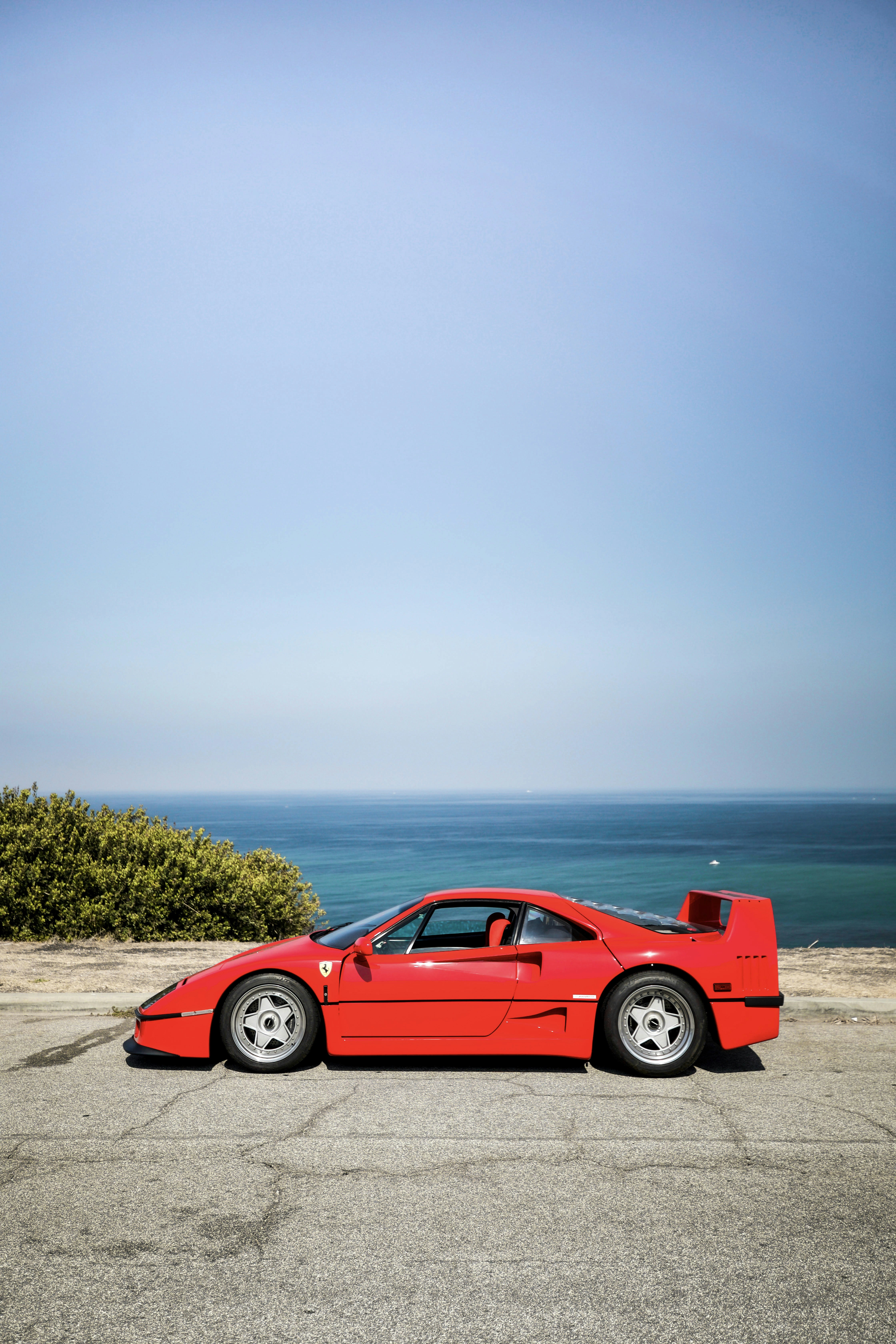 red coupe on brown sand near body of water during daytime
