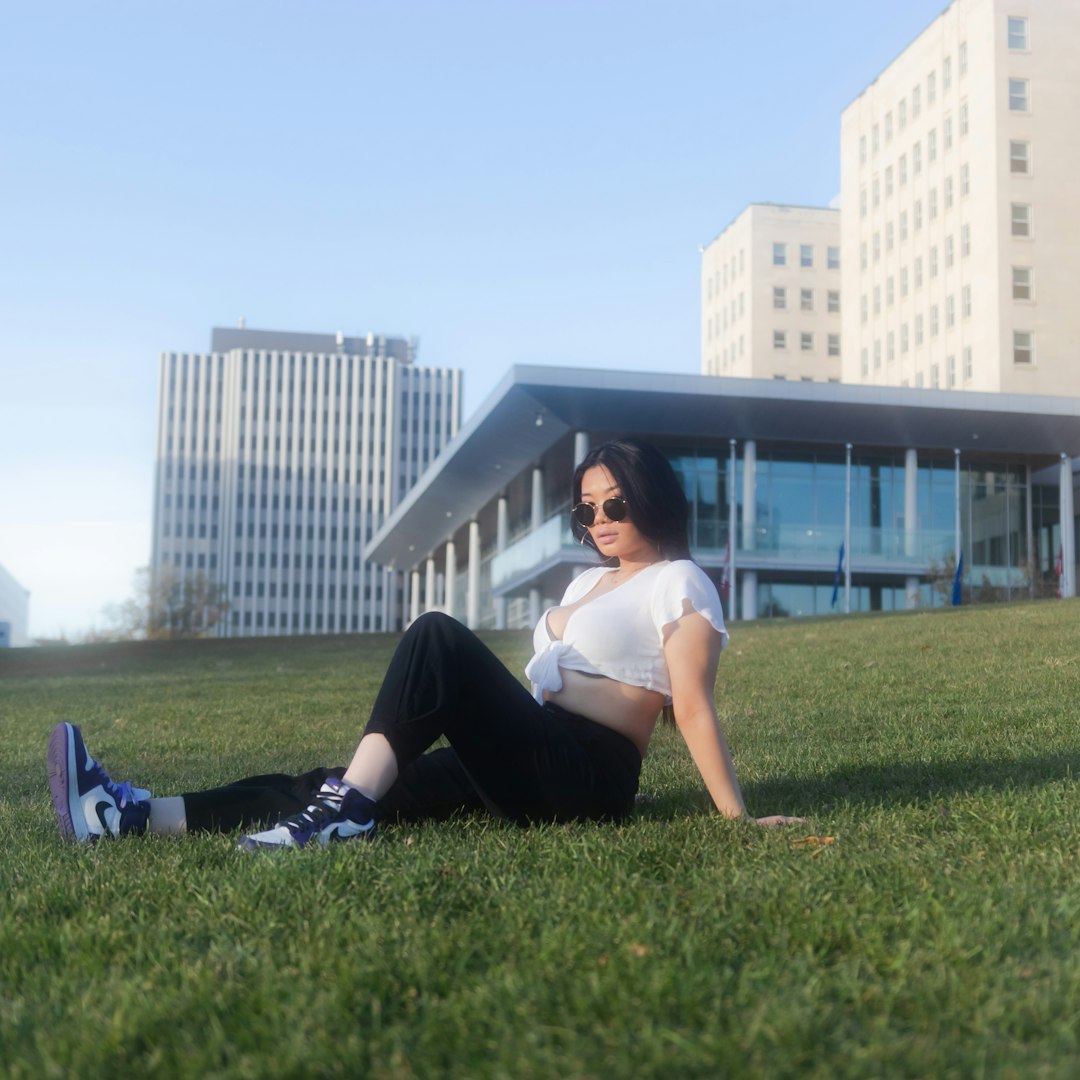 woman in white t-shirt and black pants lying on green grass field