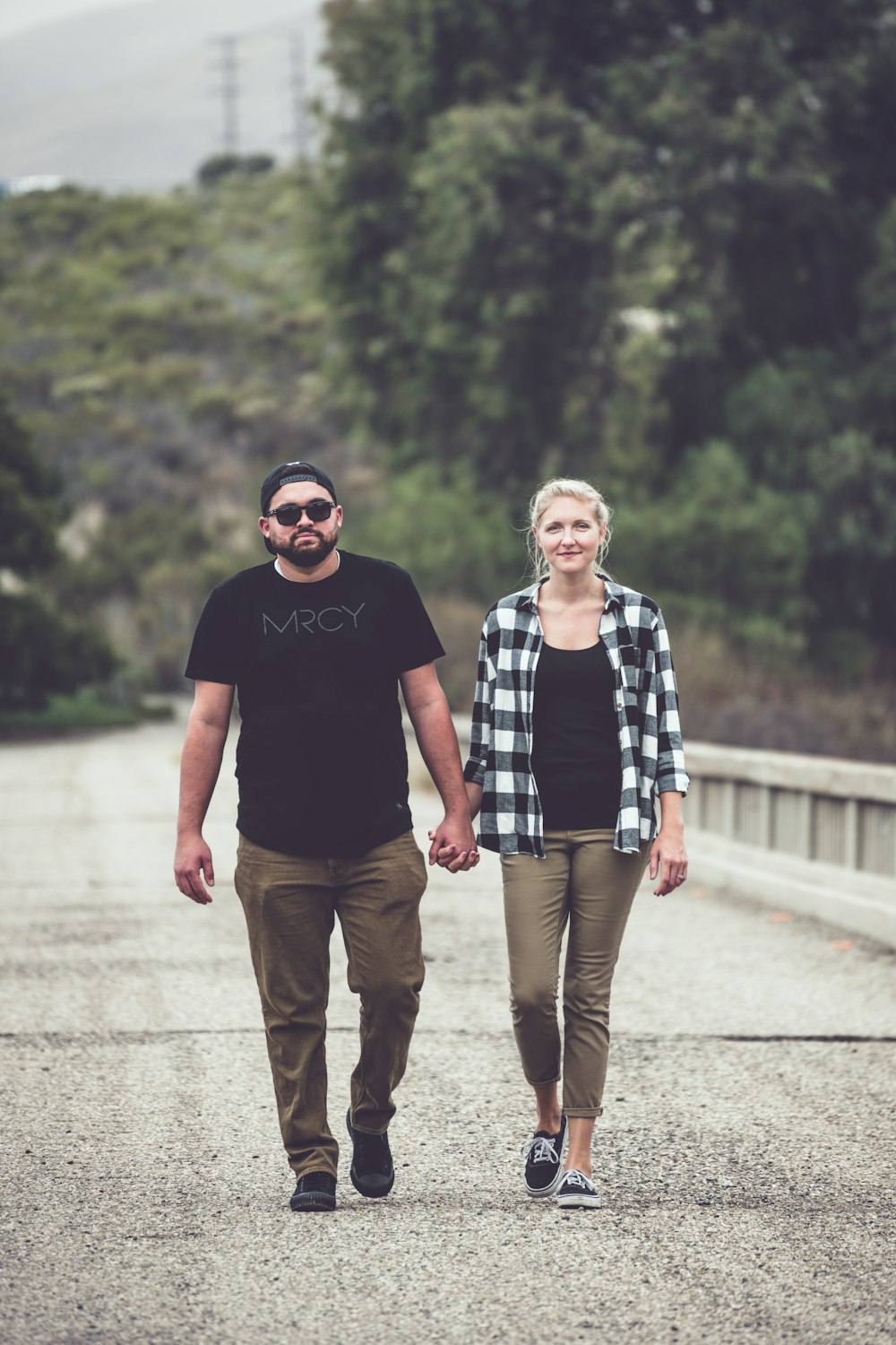 man in black crew neck t-shirt standing beside woman in blue and white plaid dress