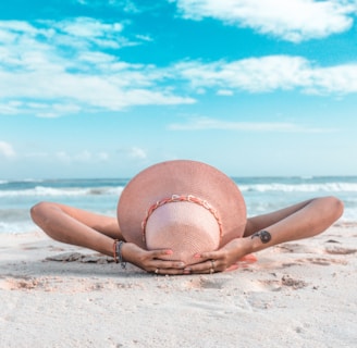 woman in brown sun hat lying on sand during daytime