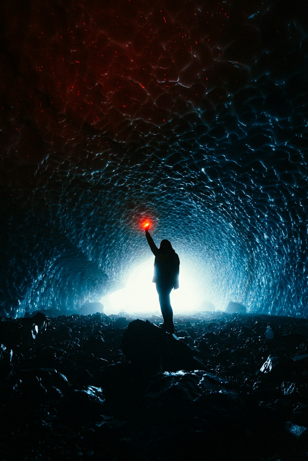 silhouette of person standing on rock with blue lights