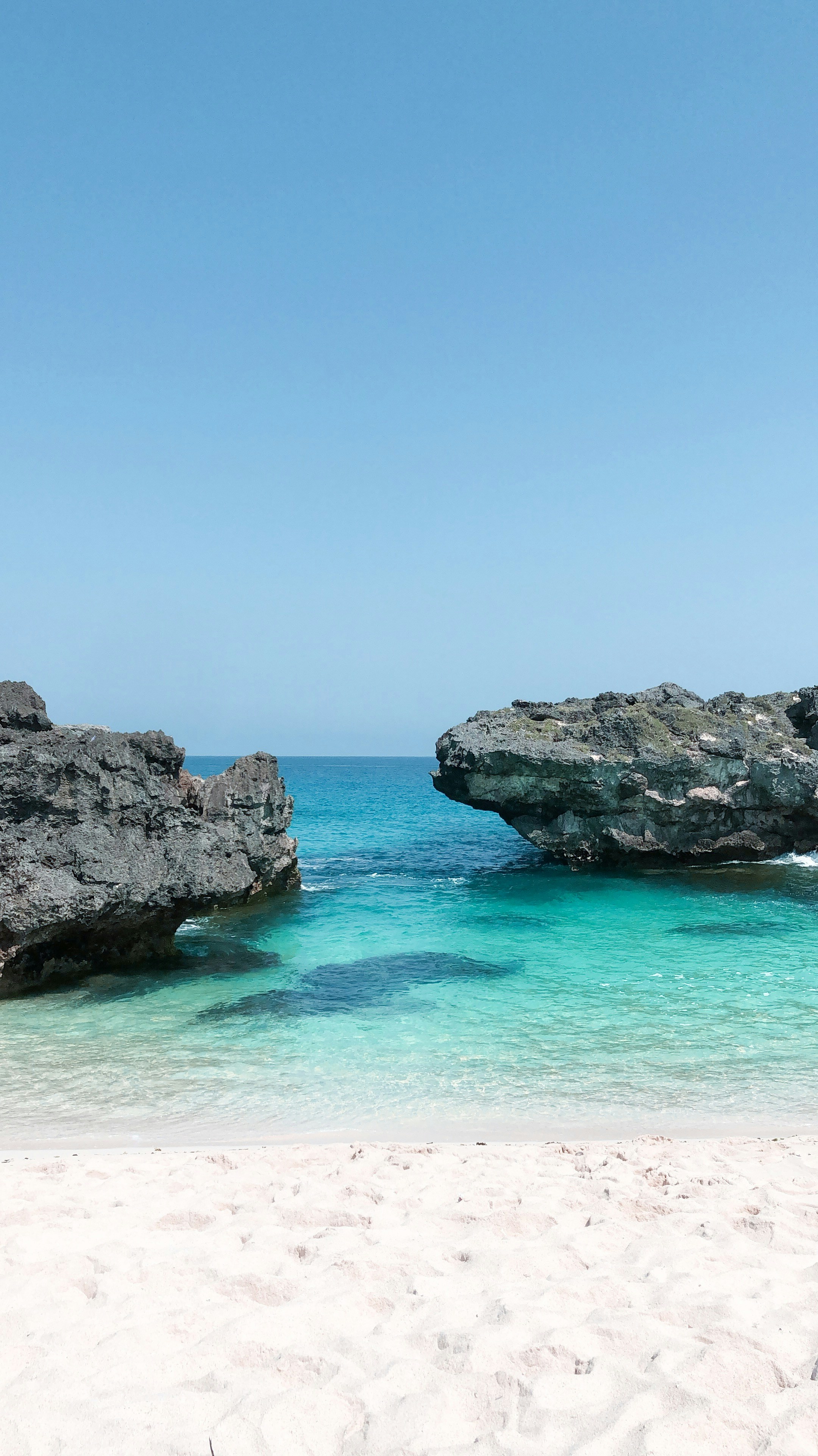 gray rocky mountain beside blue sea under blue sky during daytime