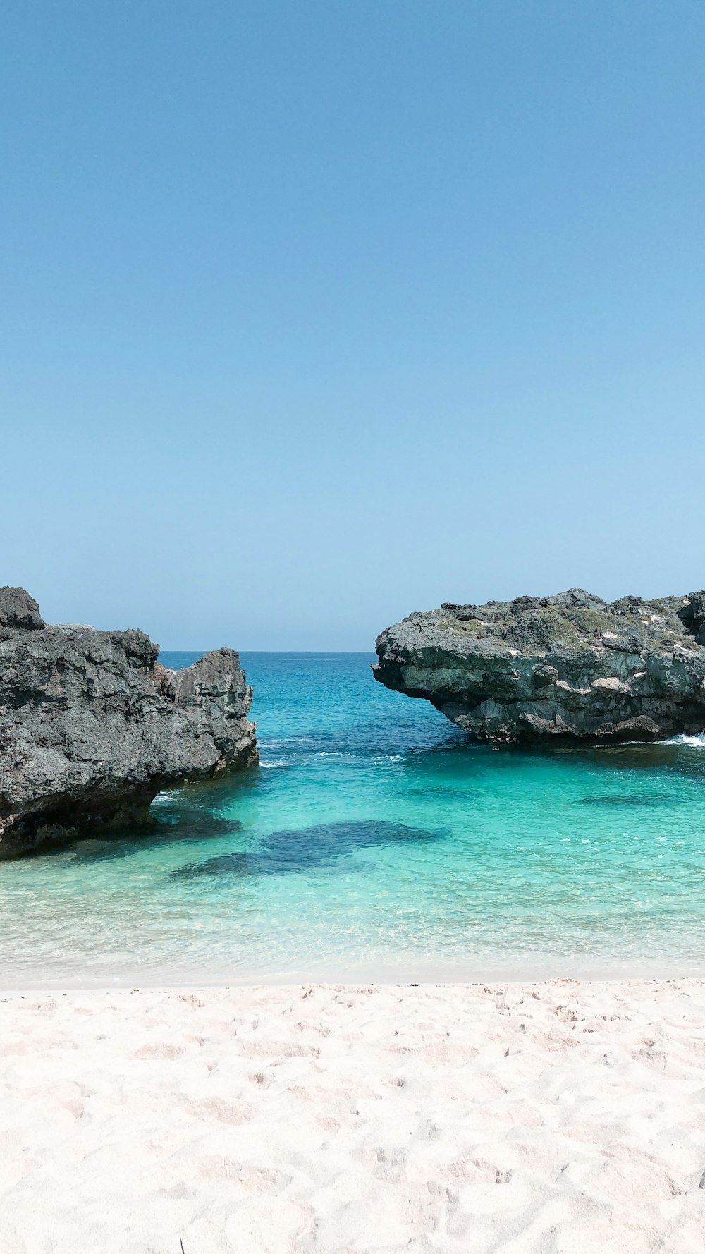 montanha rochosa cinzenta ao lado do mar azul sob o céu azul durante o dia