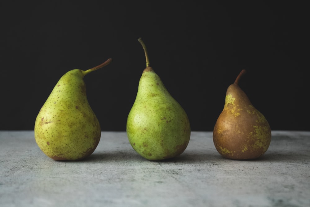 two green pear fruits on white textile