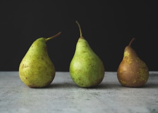 two green pear fruits on white textile