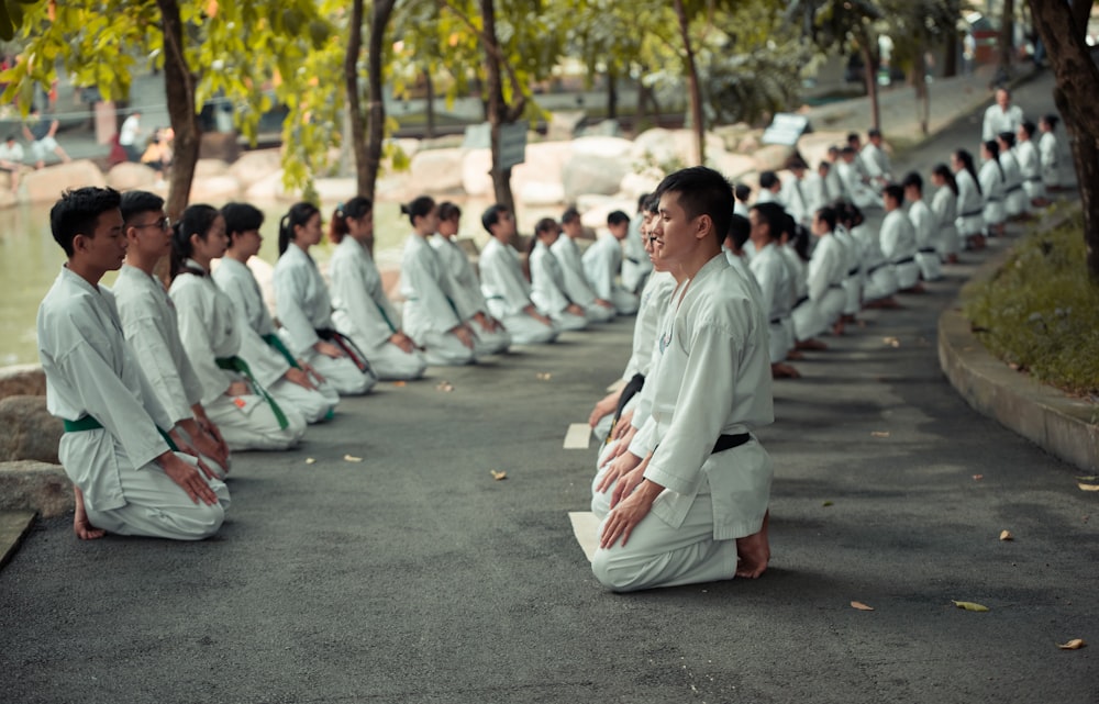 man in white robe sitting on gray concrete pavement