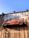 A red vintage car is affixed to a wooden wall, seemingly defying gravity. The wall bears the words 'Dependable' and 'Auto Repair' in large white letters. The car is an old model and has the phrase 'Mechanic on Duty' written on its side.