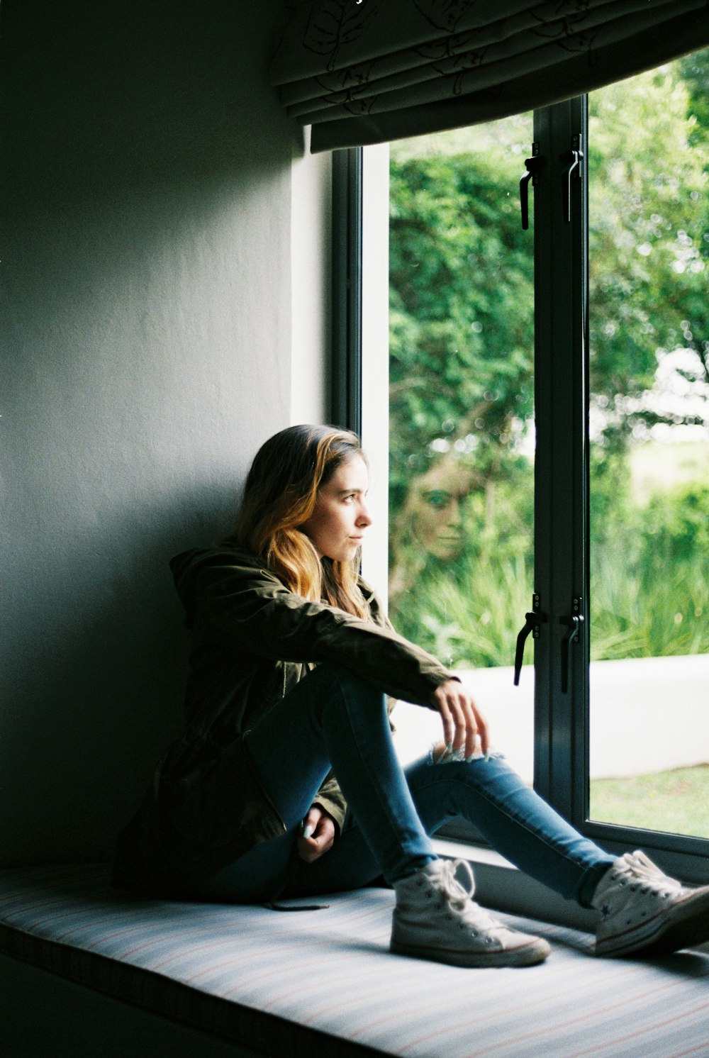 woman in black leather jacket sitting on window