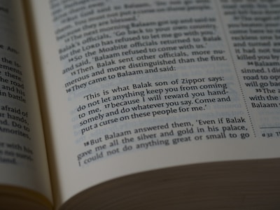 A close-up view of an open book showing a biblical text. The passage features quotes from Balak son of Zippor and Balaam.