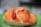 A savory pastry with a golden brown crust, topped with slices of red sausage and sprinkled with grated cheese, placed on a green surface.
