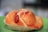 A savory pastry with a golden brown crust, topped with slices of red sausage and sprinkled with grated cheese, placed on a green surface.