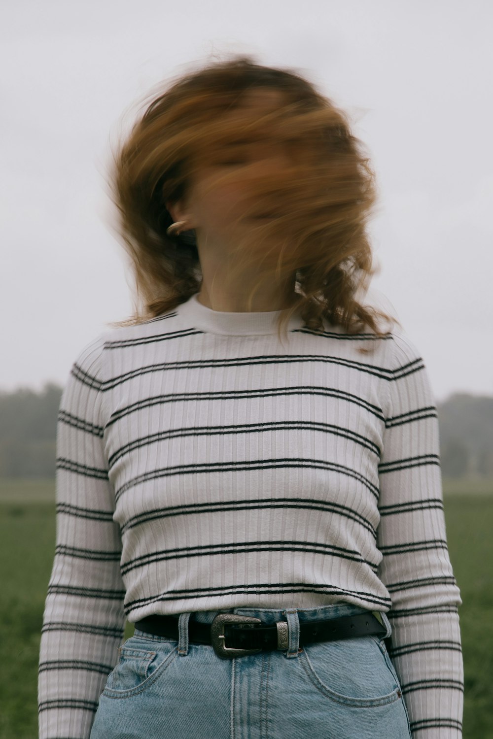 woman in white and black striped shirt standing on green grass field during daytime