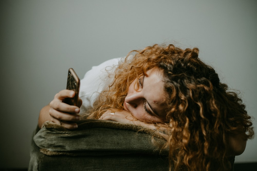 woman in gray sweater holding smartphone