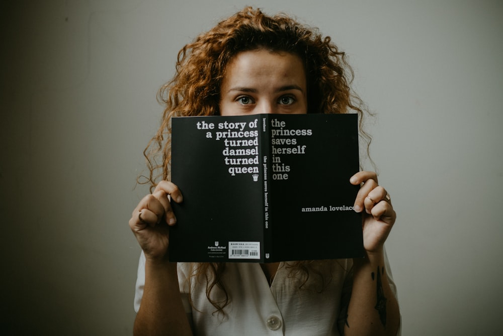 woman in white button up shirt holding black book