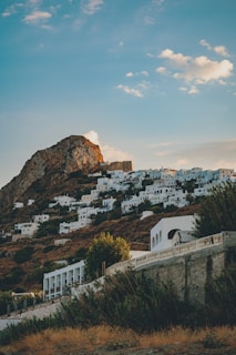 white and brown concrete buildings near brown mountain under blue sky during daytime